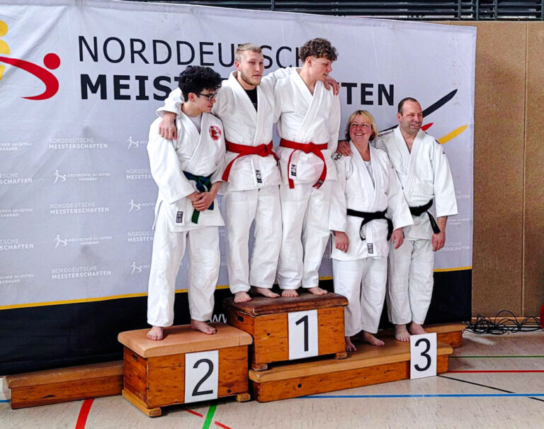 Tjark und Steffen stehen auf dem Siegerpodium der Norddeutschen Meisterschaft 2026 neben ihren Kontrahent:innen. Auszeichnung für die erfolgreichen Ju-Jutsu-Athleten.