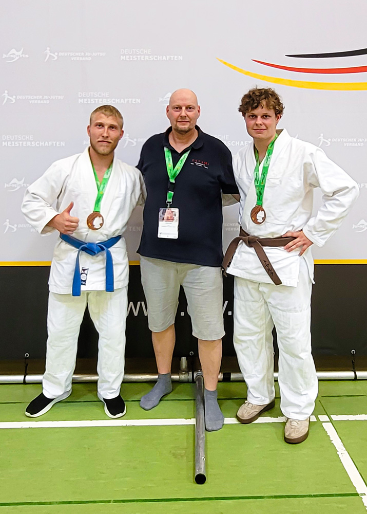 Gruppenfoto des Tatami Süpplingen e.V. bei der Deutschen Ju-Jutsu-Meisterschaft 2026 mit Trainer Roman Rose sowie den Athleten Steffen Bienias und Tjark Rose in der Mitte.